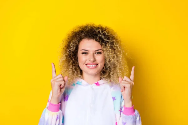 Retrato de menina de cabelos ondulados alegre atraente em pijama demonstrando anúncio espaço cópia isolado sobre fundo de cor amarela vívida — Fotografia de Stock