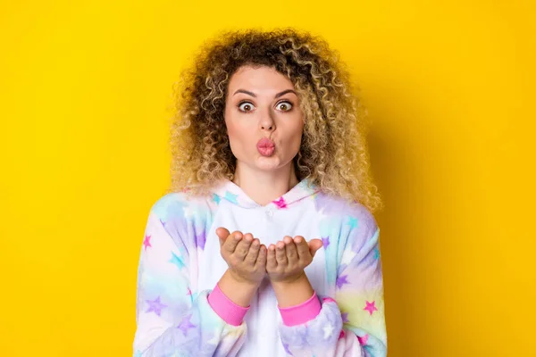 Retrato de atractiva chica de pelo ondulado sorprendida en pijama enviando beso de aire aislado sobre fondo de color amarillo brillante — Foto de Stock