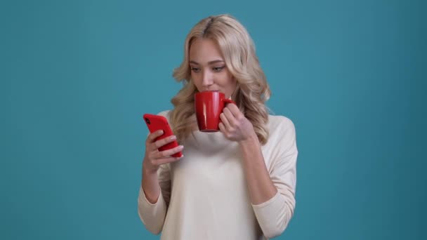 Millennial lady use device drink latte mug isolated blue color background — 비디오
