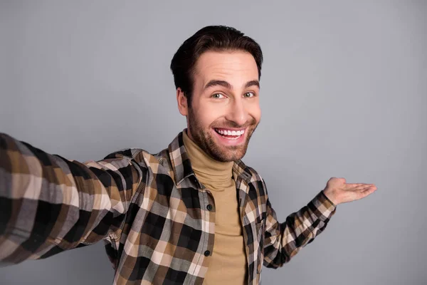 Photo of funny pretty guy dressed checkered shirt tacking selfie inviting arm you come isolated grey color background — Fotografia de Stock