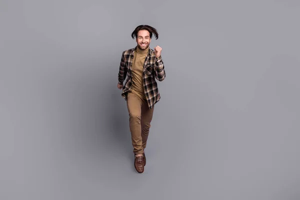 Photo of positive attractive guy dressed checkered shirt jumping high running fast isolated grey color background — Stock Photo, Image