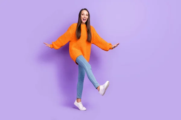 Foto de loca divertida señora inspirada caminar divertirse desgaste naranja jersey jeans zapatillas aisladas color púrpura fondo —  Fotos de Stock