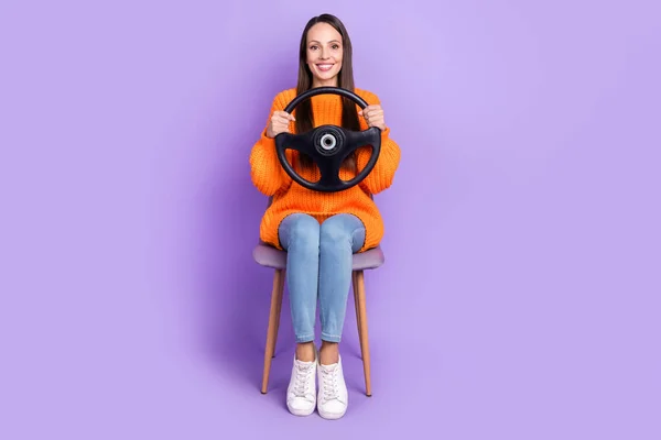 Photo of positive lady hold steering wheel sit chair prepare pass exam wear orange sweater isolated purple color background — Stok fotoğraf