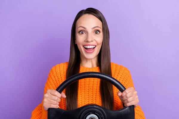 Foto de excitado conductor funky dama mantenga volante desgaste suéter naranja aislado color púrpura fondo —  Fotos de Stock
