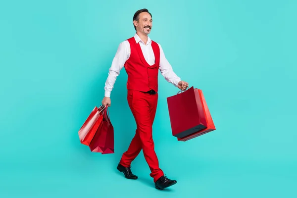 Full size profile side photo of mature cheerful man go look empty space store new collection isolated over teal color background — стоковое фото