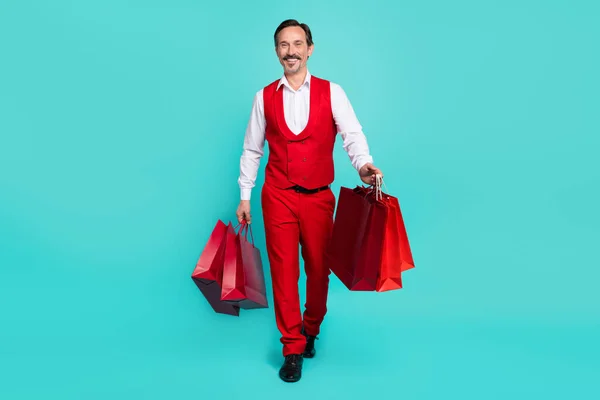 Full length photo of mature cheerful man walk shop mall holiday gift isolated over teal color background — стоковое фото