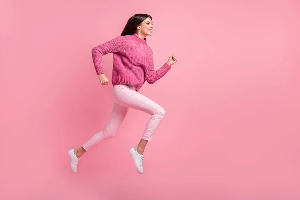 フルサイズプロフィール写真のブルネット素敵な女の子ジャンプ実行服ピンクセーターパンツスニーカー絶縁上深紅の背景 — ストック写真