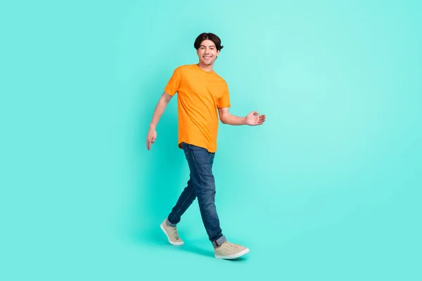 フルボディ写真の面白い茶色の髪若い男行く与える手を着用Tシャツジーンズスニーカー隔離された青の背景 — ストック写真