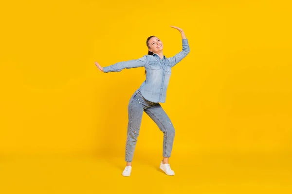 Full length φωτογραφία του αστείο γοητευτικό νεαρή γυναίκα φορούν denim πουκάμισο χαμογελώντας χορό απομονωμένο κίτρινο χρώμα φόντο — Φωτογραφία Αρχείου