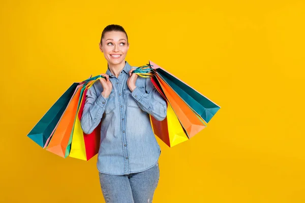 Photo of dreamy happy nice young woman hold sale bags look empty space isolated on yellow color background — 스톡 사진