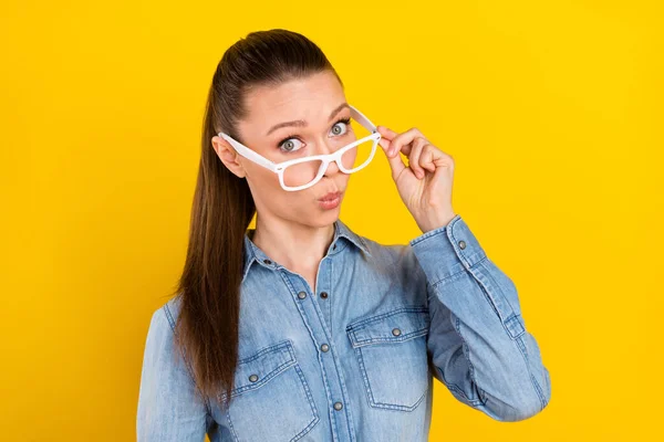 Photo of impressed pretty young lady dressed jeans shirt arm spectacles big eyes isolated yellow color background — Stockfoto