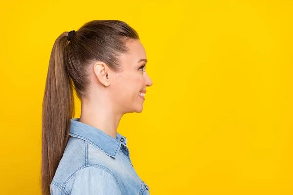 Photo of shiny adorable young lady dressed jeans shirt looking empty space smiling isolated yellow color background — Photo