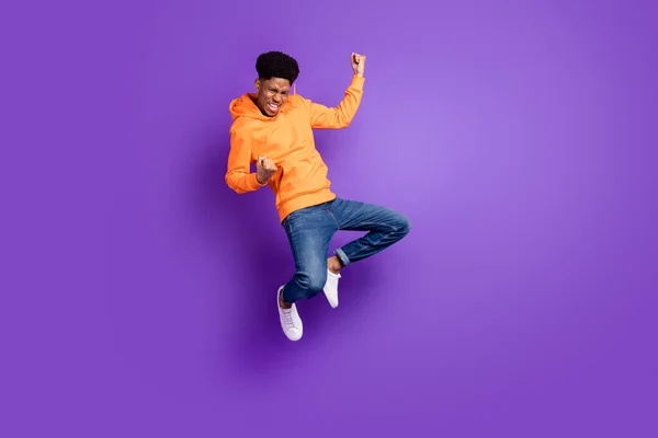 Full length photo of young crazy dark skin man jump up air fists winner celebrate isolated on violet color background — Fotografia de Stock