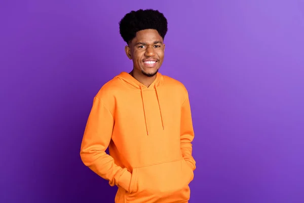 Foto de hombre de piel oscura joven feliz cogido de la mano naranja sudadera con capucha sonrisa estilo calle aislado sobre fondo de color púrpura — Foto de Stock