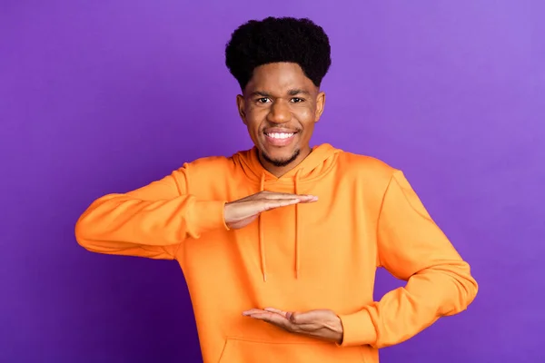 Foto di funky brunet millennial ragazzo mani misura indossare felpa arancione isolato su sfondo di colore viola — Foto Stock