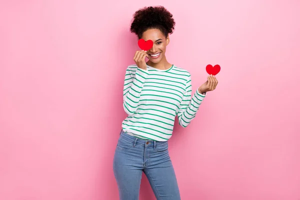 Photo of lovely bun hairstyle young lady hold hearts wear striped shirt jeans isolated on pink color background — Fotografia de Stock