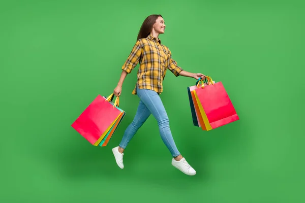 Full body profile photo of pretty carefree lady look empty space hold packages isolated on green color background — Fotografia de Stock