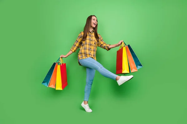 Full size portret van zorgeloze shopper dame kijken leeg ruimte hebben goed humeur geïsoleerd op groene kleur achtergrond — Stockfoto