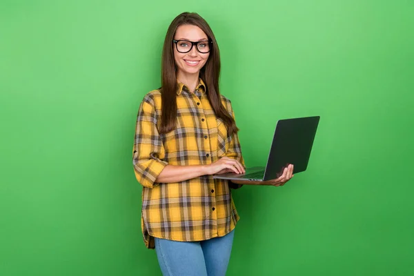 Portret van charmante vrolijke meisje houden netbook tand glimlach kijken camera geïsoleerd op groene kleur achtergrond — Stockfoto