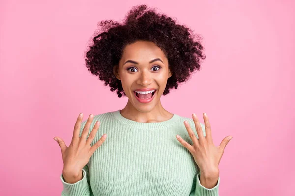 Foto de joven feliz piel oscura mujer asombrada levantar las manos noticias impactada aislado en el fondo de color rosa —  Fotos de Stock