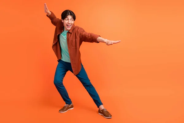 Full size photo of cheerful smiling handsome man dancing fooling around isolated on orange color background — Photo