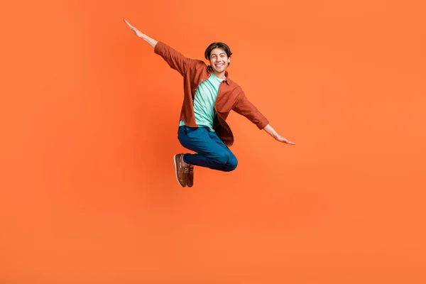 Full size photo of smiling good mood childish guy jumping fooling around carefree isolated on orange color background — Stok fotoğraf