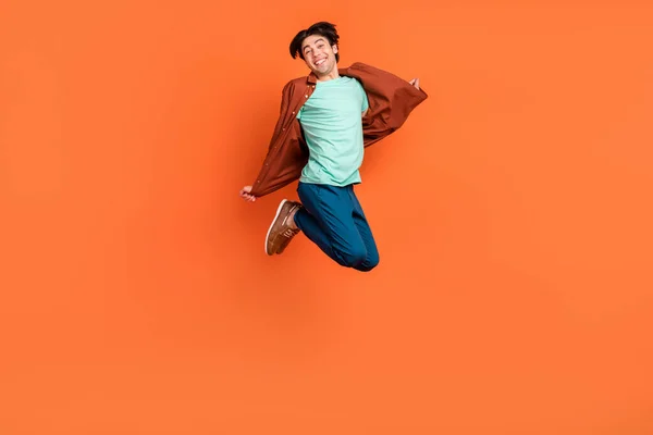 Full size photo of funky smiling cheerful carefree man jumping enjoy summer vacation isolated on orange color background — Stockfoto