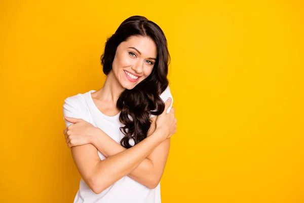 Portrait of attractive cheerful girl hugging herself copy space isolated over bright yellow color background — Zdjęcie stockowe