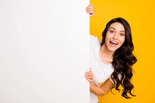 Porträtt av attraktiva glada vågiga hår flicka som håller stora styrelsen kopia tomt utrymme erbjuda isolerade över ljusa gula färg bakgrund — Stockfoto