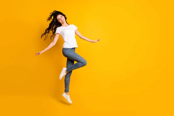 밝은 노란색 배경 위에 따로 떨어져 즐거운 춤을 추며 뛰어오르는 아름다운 소녀의 전체 몸길이 사진 — 스톡 사진