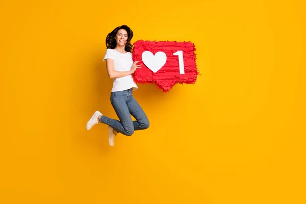 Full length body size view of lovely cheerful girl jumping holding red like board isolated over bright yellow color background — Stock Fotó