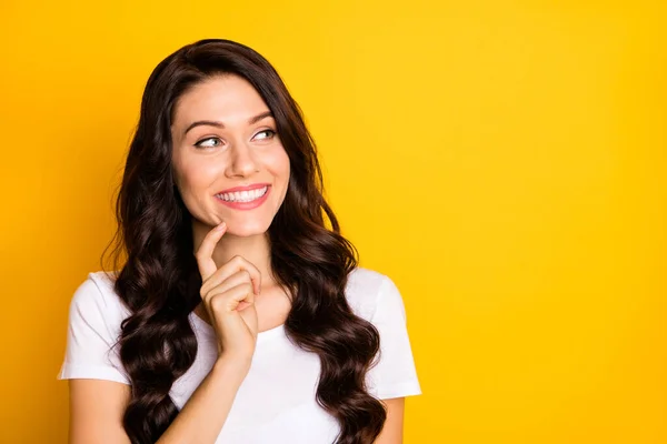 Photo of sweet funny young lady dressed white t-shirt finger chin looking empty space isolated yellow color background — Stockfoto