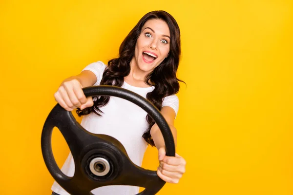 Portrait of pretty cheerful amazed wavy-haired girl holding steering wheel having fun isolated over bright yellow color background — Stok fotoğraf