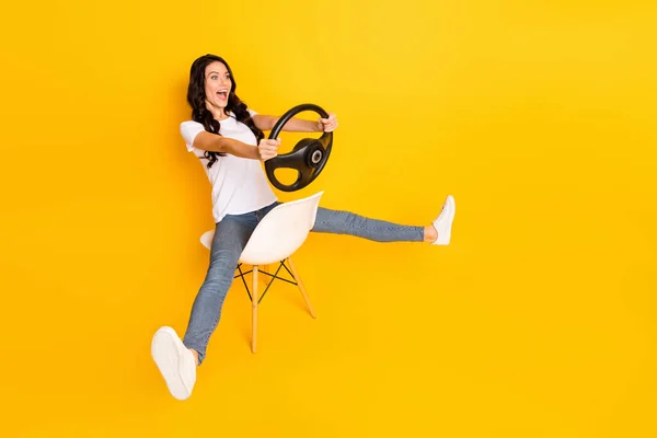 Vista completa del tamaño del cuerpo de la encantadora chica alegre sentada sosteniendo el volante divirtiéndose aislada sobre un fondo de color amarillo brillante —  Fotos de Stock