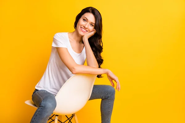 Portrait of lovely cheerful girl sitting in chair copy empty space isolated over bright yellow color background — стоковое фото