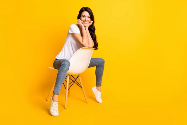 Retrato de chica alegre alegre atractiva sentada en silla disfrutando de espacio de copia aislado sobre fondo de color amarillo brillante —  Fotos de Stock