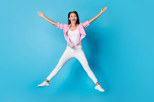 Photo of lady jump raise hands star pose open mouth wear pink striped shirt trousers sneakers isolated blue background — Stock Photo, Image