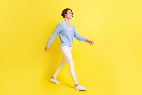 Foto de chica encantadora caminar mirada espacio vacío desgaste azul chaqueta pantalones calzado aislado color amarillo fondo —  Fotos de Stock