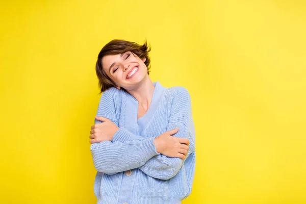 Foto de señora ojos cerrados abrazar hombros sonrisa dentada usar cárdigan azul aislado color amarillo fondo — Foto de Stock