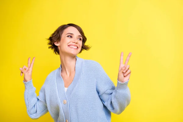 Φωτογραφία του νεαρού ενθουσιασμένοι κορίτσι ευτυχής θετικό χαμόγελο δείχνουν την ειρήνη δροσερό v-σημάδι ματιά κενό χώρο απομονωμένο πάνω από κίτρινο χρώμα φόντο — Φωτογραφία Αρχείου