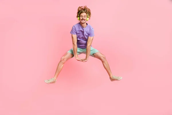 Longitud completa cuerpo tamaño vista de atractivo alegre chico saltando escuchar pop hit divertirse aislado sobre rosa pastel color fondo — Foto de Stock