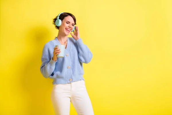 Portrait of attractive cheerful girl drinking beverage listening bass hit having fun copy space isolated over bright yellow color background — Stockfoto