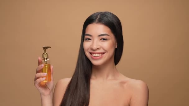 Senhora coreana aplicar sedoso corte de cabelo spray máscara isolado pastel cor fundo — Vídeo de Stock