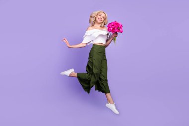 Photo of girlfriend lady jump hold bunch flowers go wear white blouse flared trousers isolated purple color background clipart