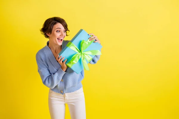 Portrait de charmante fille joyeuse étonnée tenant dans les mains espace de copie boîte cadeau isolé sur fond de couleur jaune vif — Photo