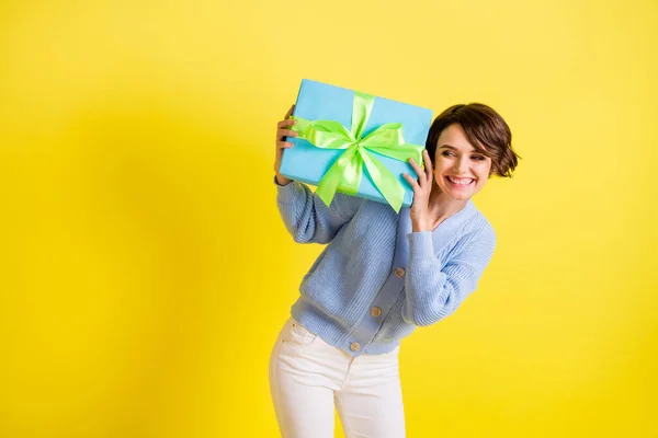 Retrato de encantadora señora positiva mirada mano mantenga giftbox cerca de la oreja radiante sonrisa aislada en el fondo de color amarillo —  Fotos de Stock