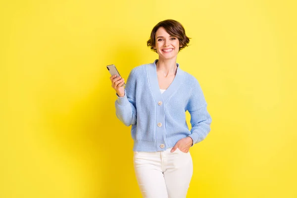 Photo of adorable positive person put hand in pocket hold phone toothy smile isolated on yellow color background — Stock Fotó