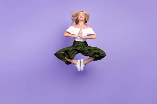 Photo of lady jump meditate close eyes lotus pose wear white blouse flared trousers isolated purple color background — Stockfoto