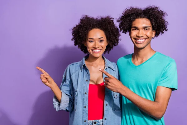 Foto av positiva unga glada afro amerikanska människor peka finger tomt utrymme isolerad på violett färg bakgrund — Stockfoto