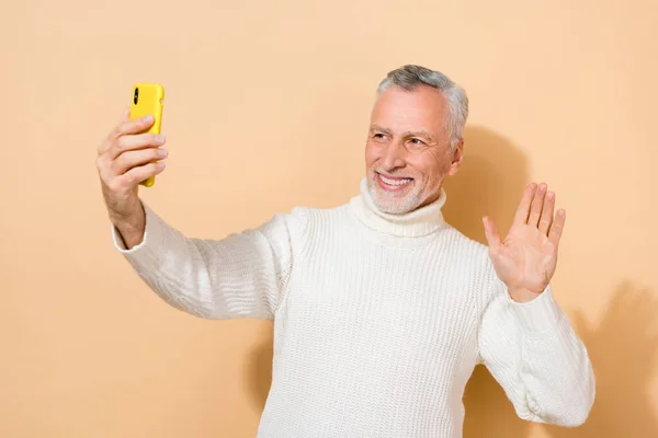 Portrait of attractive cheerful grey-haired man making taking selfie waving hi hello video call isolated over beige pastel color background — Stock Photo, Image